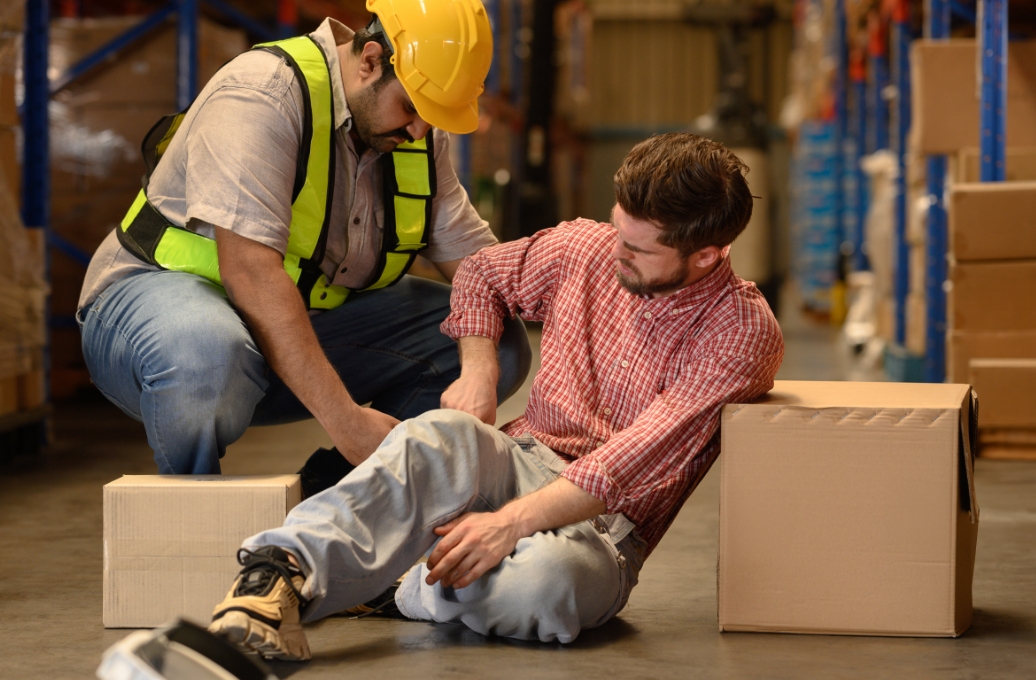 Man falling on the job and his coworker is helping him assess the situation.