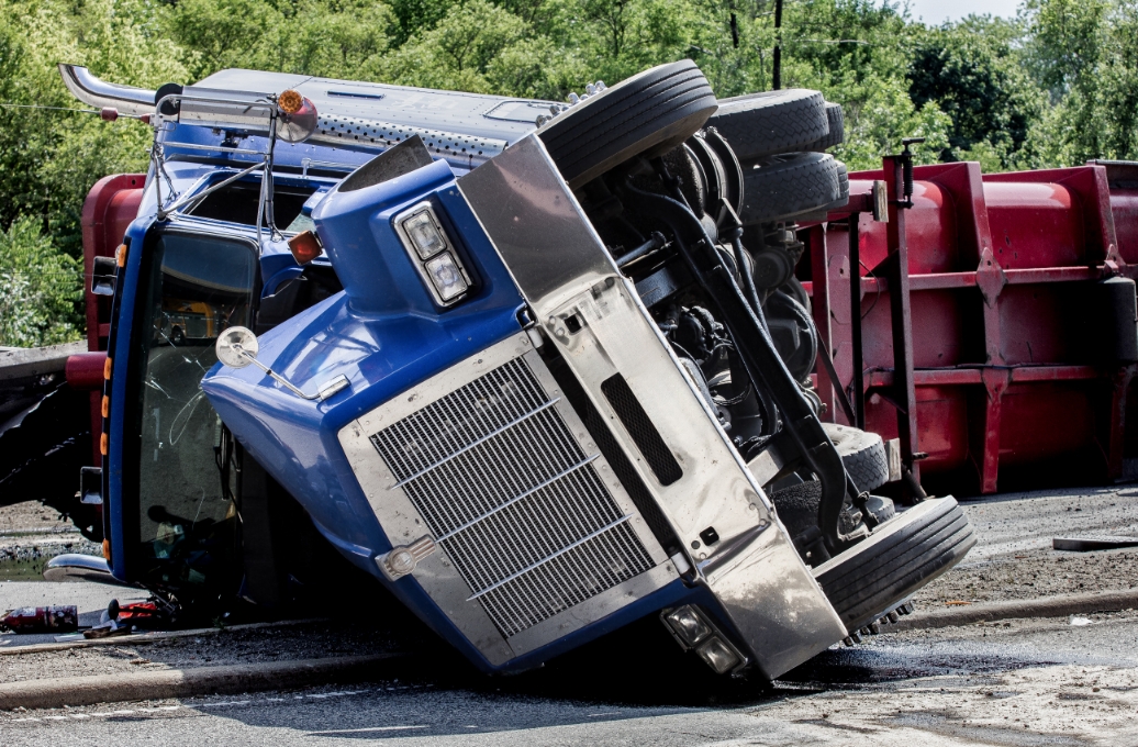 Blue truck rolled over onto its side on a street.