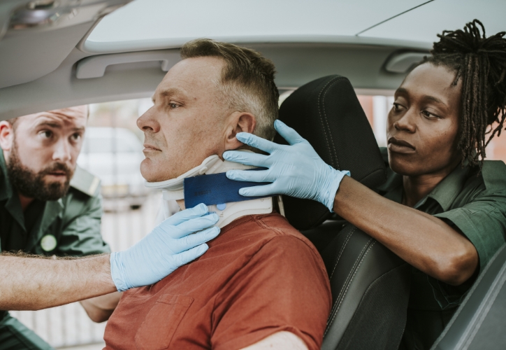 Man receiving emergency treatment in his car after a car accident.