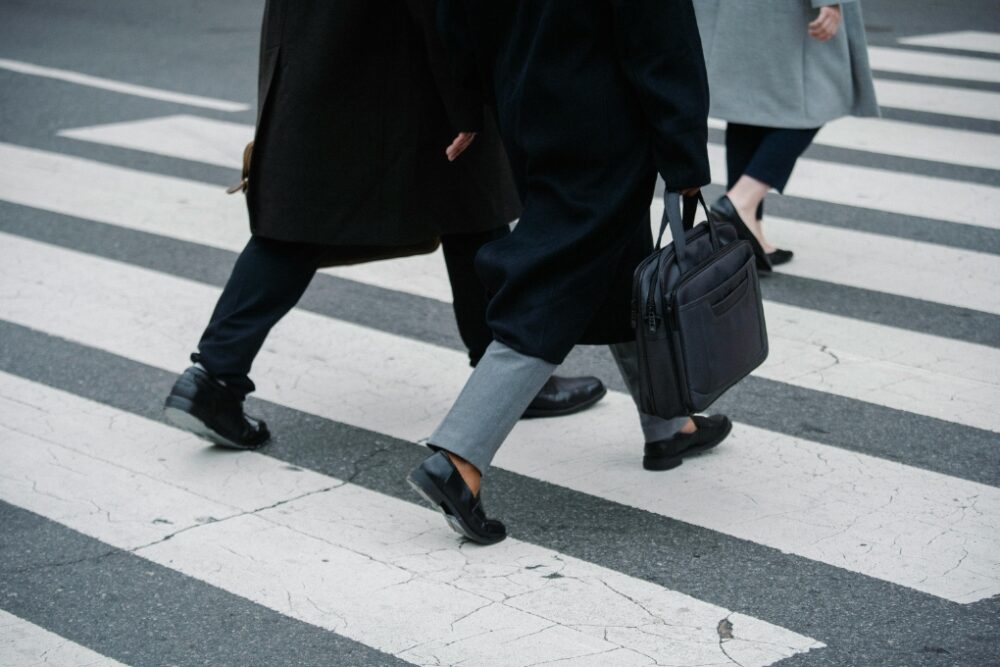 Three people from the waist down walking across a cross walk.