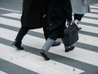 Three people from the waist down walking across a cross walk.