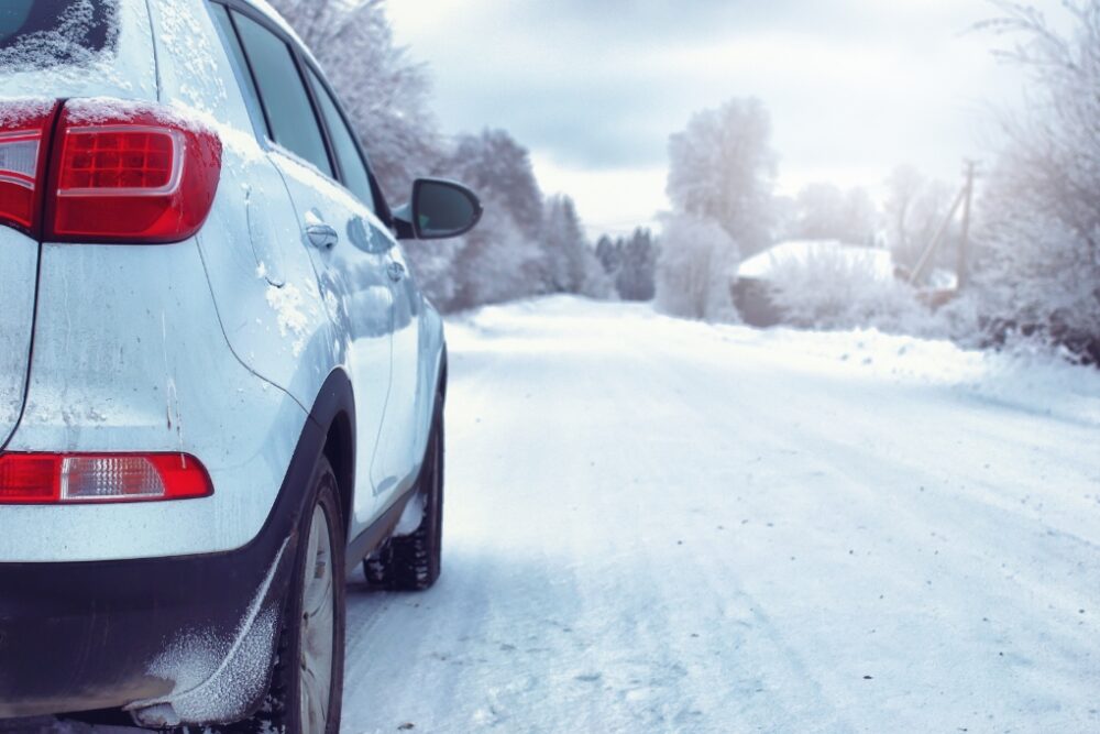 White car driving on a snowy road.