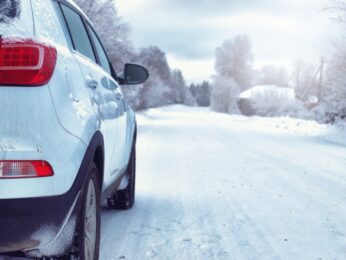 White car driving on a snowy road.