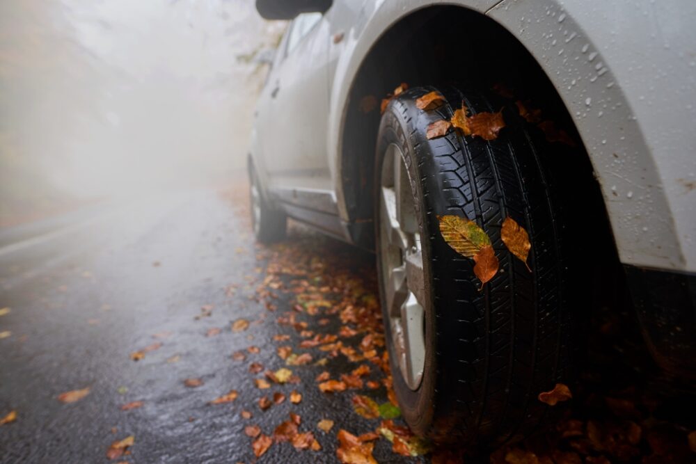 A tire on a car skidding on the road because of wet leaves.